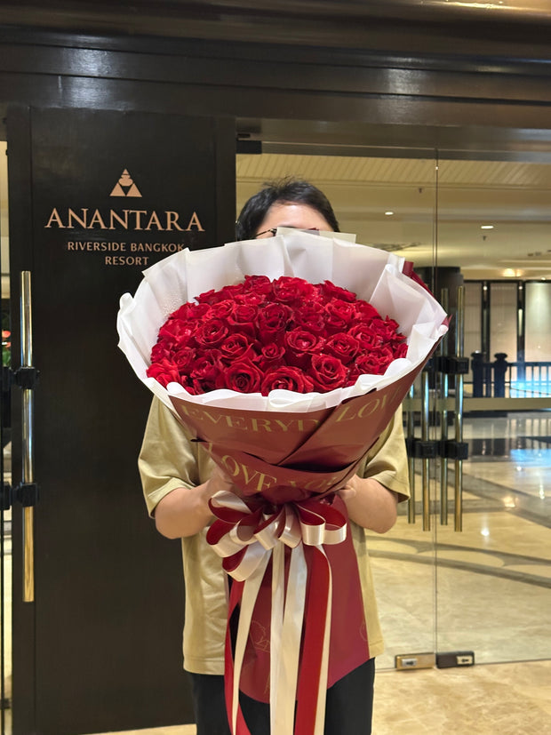 Man holding a luxurious 100 red roses bouquet – DP FLOWERS BANGKOK hotel flower delivery for VIP and special occasions