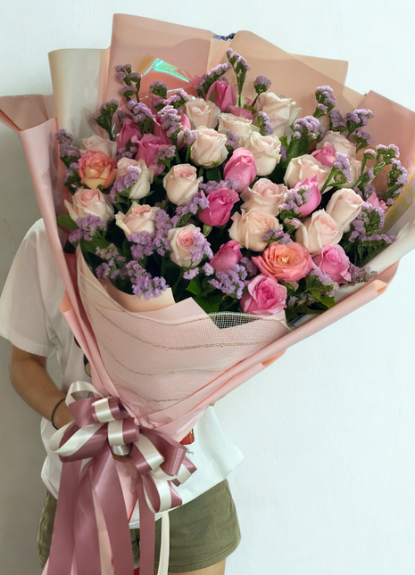 Soft pink and cream roses bouquet with purple statice wrapped in dusty pink paper - gentle flower delivery Bangkok | DP FLOWERS BANGKOK