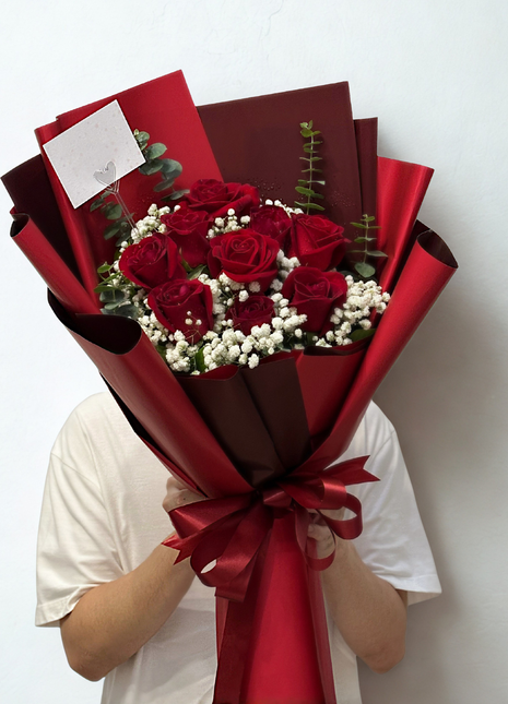 Nine premium red roses bouquet with baby's breath and eucalyptus in deep red wrapping held by person - eternal love Valentine's Day delivery Bangkok | DP FLOWERS BANGKOK