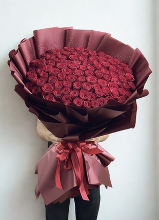 Spectacular bouquet of 100 premium red roses in massive dome arrangement with deep red wrapping and red ribbon held by person - ultimate Valentine's Day delivery Bangkok | DP FLOWERS BANGKOK