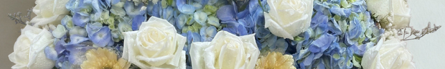 Elegant white wicker basket filled with white roses, blue hydrangeas and yellow flowers with navy ribbon - luxury flower delivery Bangkok | DP FLOWERS BANGKOK