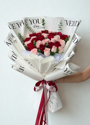 Romantic red and pink roses bouquet wrapped in artistic printed newspaper paper with burgundy ribbons and illustration tag - unique flower delivery Bangkok | DP FLOWERS BANGKOK