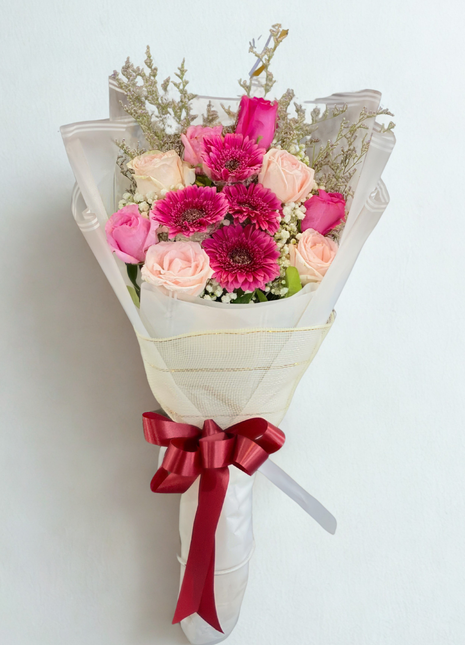 Mixed bouquet with peach roses, pink roses and fuchsia gerberas wrapped in white paper with red ribbon - fresh flower delivery Bangkok | DP FLOWERS BANGKOK