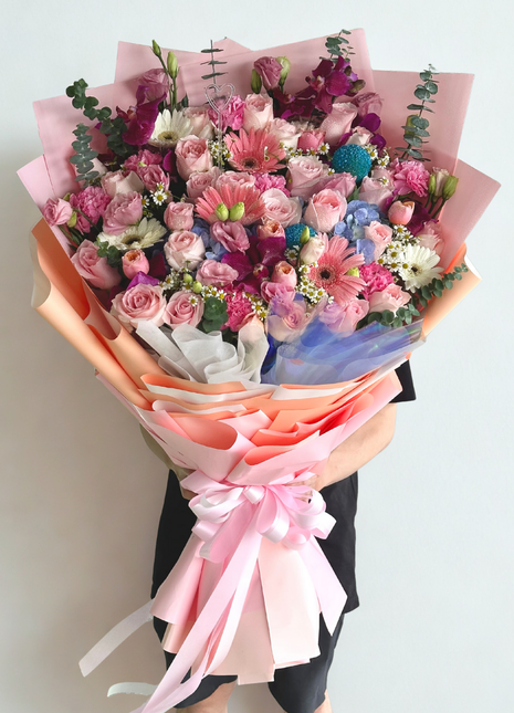 Luxury colorful mixed flower bouquet with pink roses, gerberas, lisianthus, and blue hydrangeas wrapped in gradient pink paper - premium flower delivery Bangkok | DP FLOWERS BANGKOK