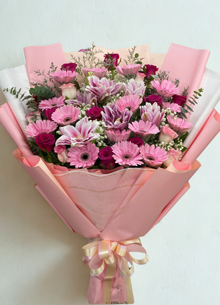 Vibrant pink gerbera daisies, pink lilies and fuchsia roses bouquet wrapped in pink paper with cream ribbon - flower delivery Bangkok | DP FLOWERS BANGKOK