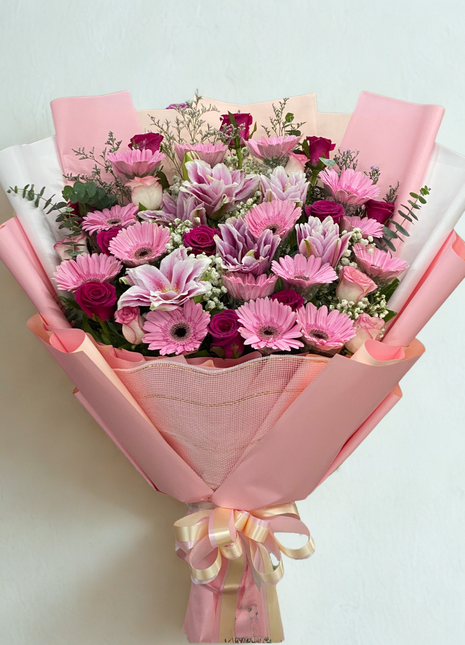 Vibrant pink gerbera daisies, pink lilies and fuchsia roses bouquet wrapped in pink paper with cream ribbon - flower delivery Bangkok | DP FLOWERS BANGKOK