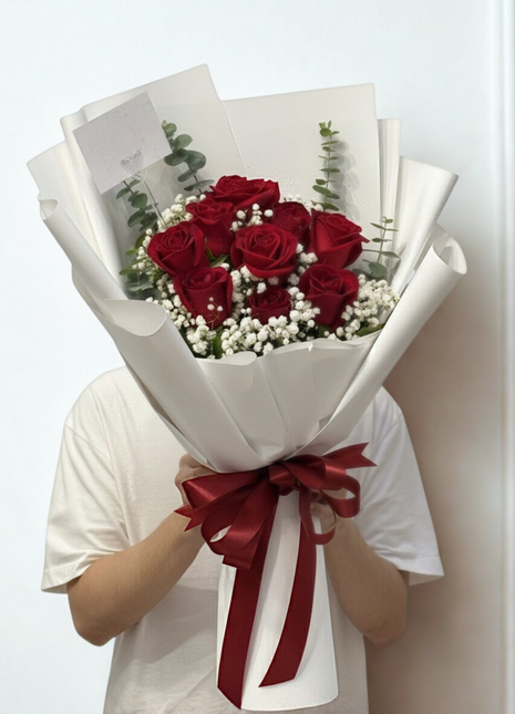 Nine premium red roses bouquet with baby's breath and eucalyptus in white wrapping held by person - eternal love Valentine's Day delivery Bangkok | DP FLOWERS BANGKOK