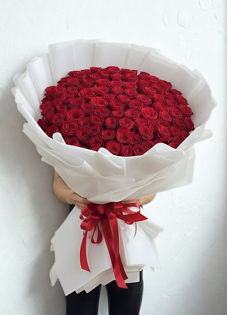 Spectacular bouquet of 100 premium red roses in massive dome arrangement with white wrapping and red ribbon held by person - ultimate Valentine's Day delivery Bangkok | DP FLOWERS BANGKOK