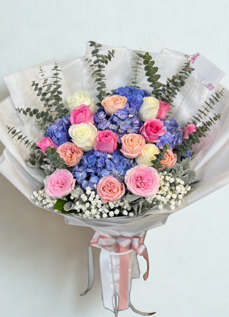 Colorful mixed roses and blue hydrangea bouquet with eucalyptus wrapped in white paper - vibrant flower delivery Bangkok | DP FLOWERS BANGKOK