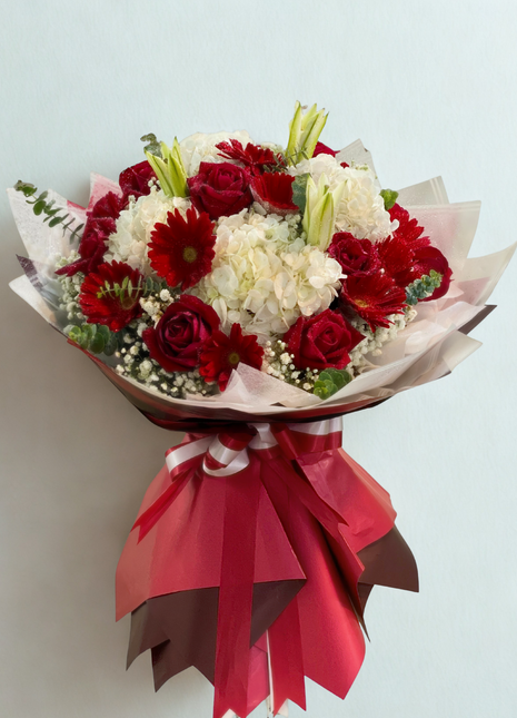 Vibrant red roses, gerbera daisies and white hydrangeas bouquet wrapped in burgundy and pink paper with red ribbon - celebration flower delivery Bangkok | DP FLOWERS BANGKOK