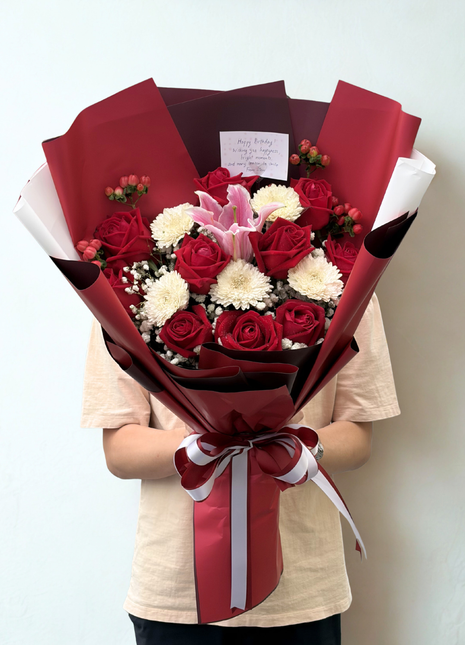 Red roses and pink stargazer lily bouquet with white chrysanthemums wrapped in deep crimson paper with red white ribbon - flower delivery Bangkok | DP FLOWERS BANGKOK