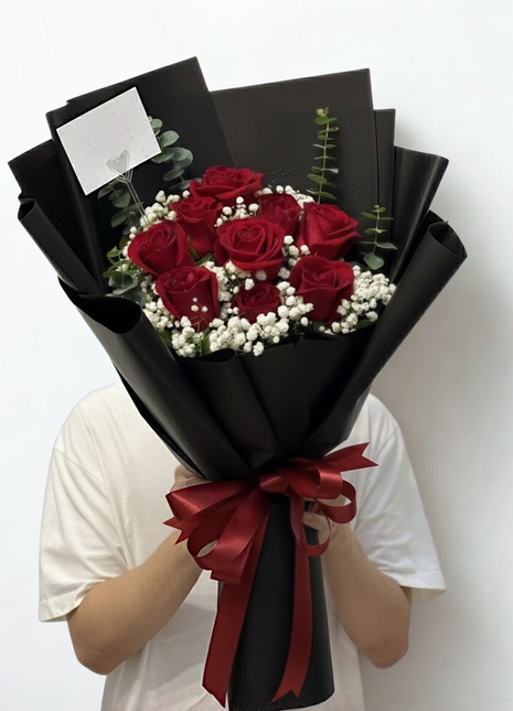 Nine premium red roses bouquet with baby's breath and eucalyptus in luxury black wrapping held by person - eternal love Valentine's Day delivery Bangkok | DP FLOWERS BANGKOK