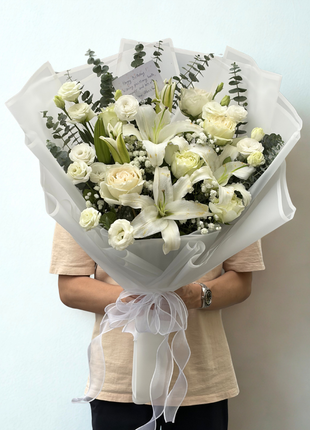 All-white oriental lilies, roses and lisianthus bouquet with eucalyptus wrapped in frosted white paper with organza ribbon - flower delivery Bangkok | DP FLOWERS BANGKOK